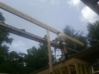 Carpenter setting a ridge beam over a new addition frame — Ice Dam Removal by Roofing Brothers in Alkol