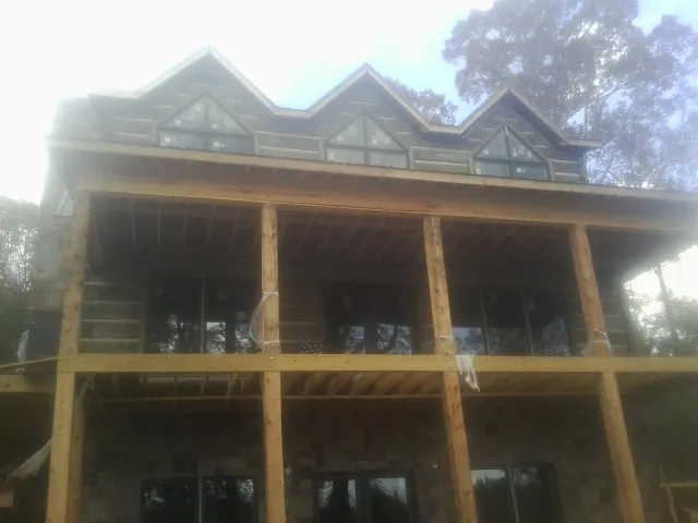 Dormers and porch framing on a large log home under construction — Roof Coating work by our crew in Alkol