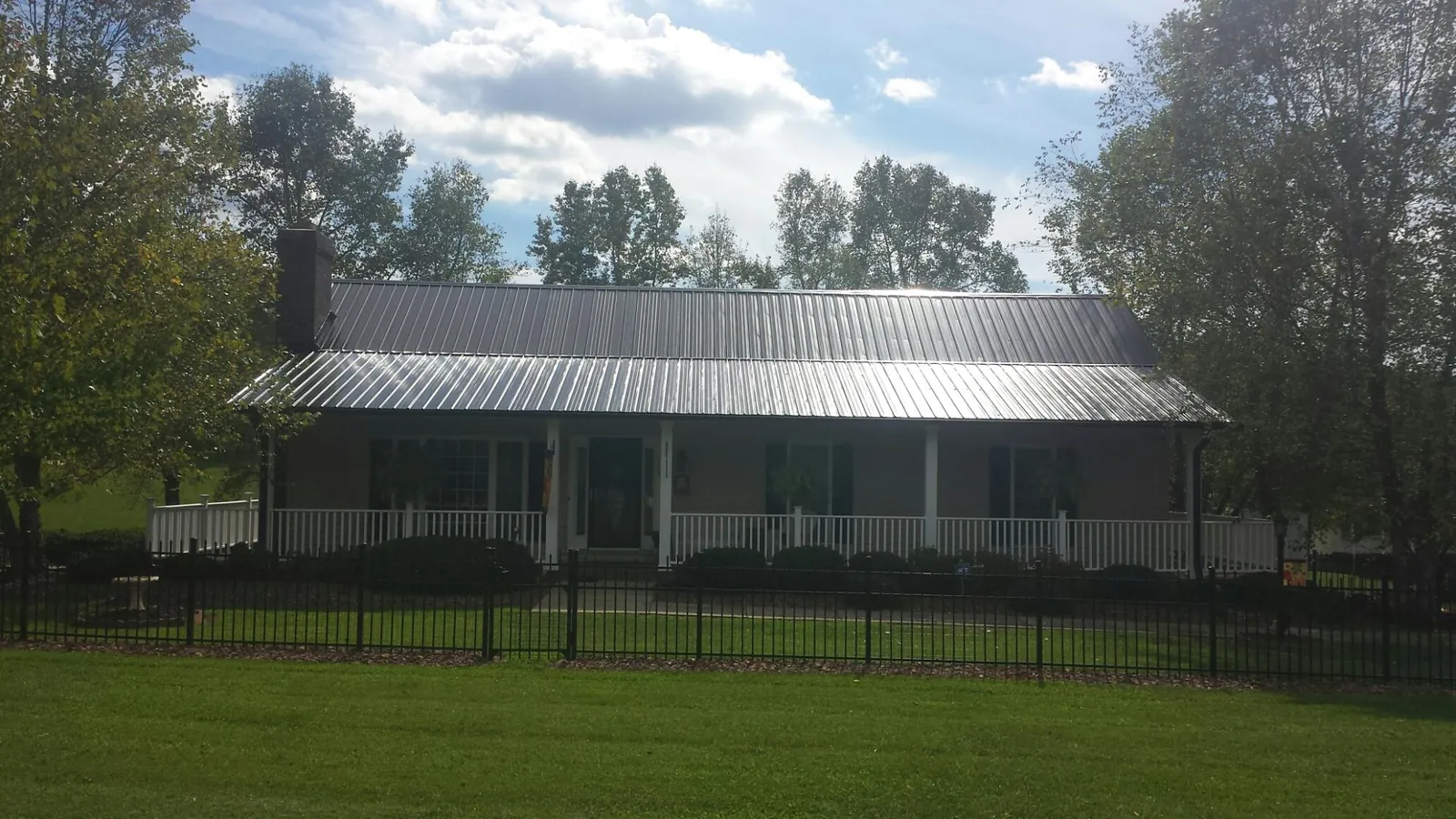Gray metal roof on a brick ranch with a full width front porch — Gutter Guard Installation work by our crew in Alkol