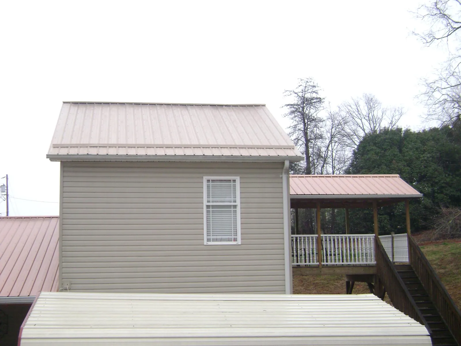 Tan metal roofs on a two story addition and attached porch, from a Roof Replacement job in Alkol