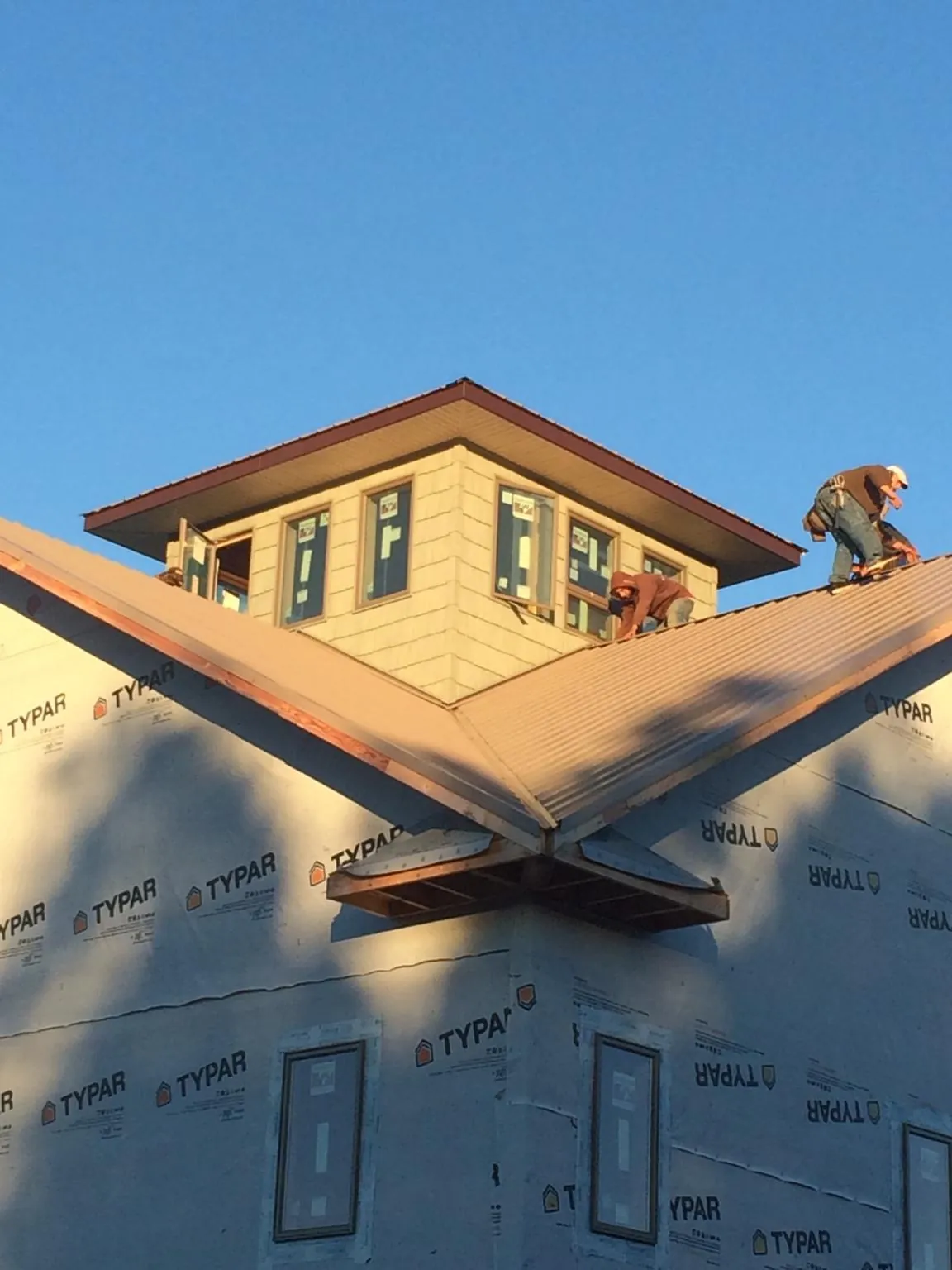 Roofers working around a rooftop cupola on a new metal roof at sunset — Roof Waterproofing in Alkol by Roofing Brothers